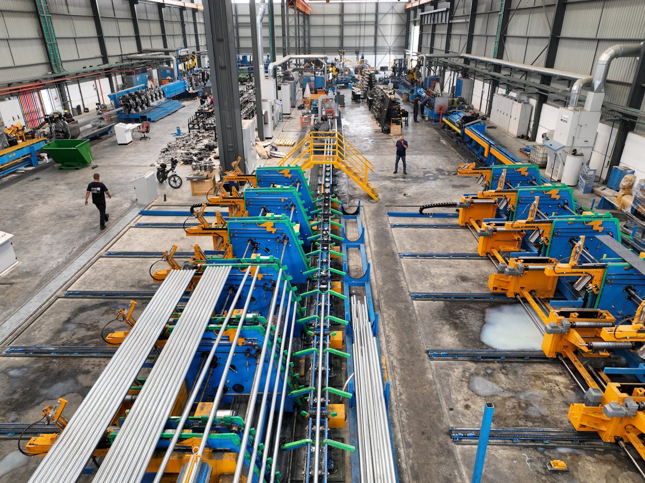 gallery-05 Aerial view of a large manufacturing plant interior with machinery and workers.